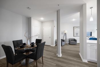 A dining room with a table set for two and a kitchen area in the background.
